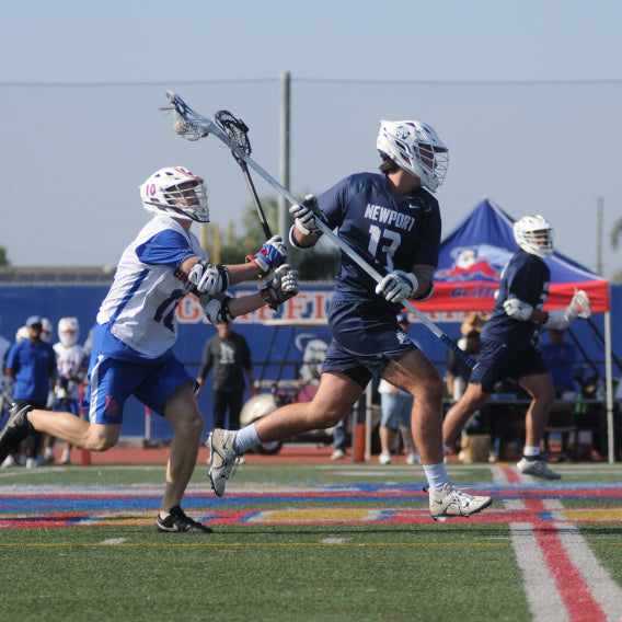 Newport Harbor Lacrosse player running with a ball, chased by an opponent